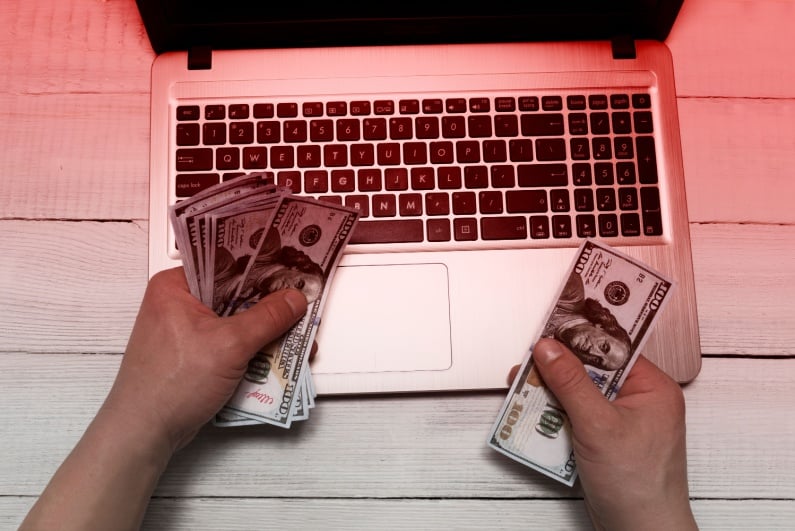 Person holding cash with laptop