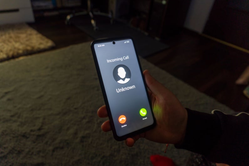 Holding a phone with _Unknown_ caller ID