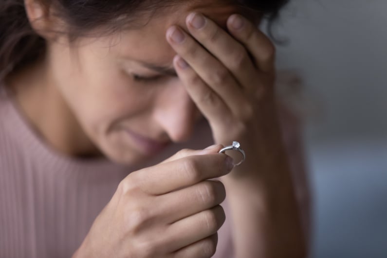 Sad woman holding engagement ring