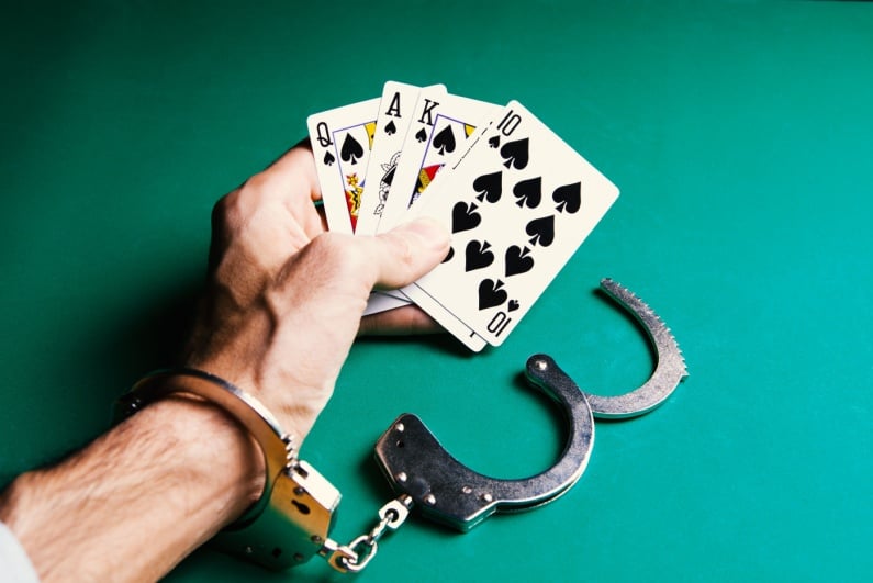 Handcuffed hand holding cards