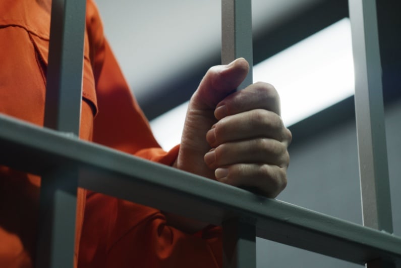 Inmate holding jail cell bars