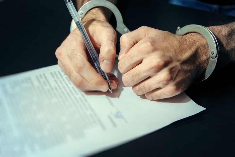 Person in handcuffs signing contract