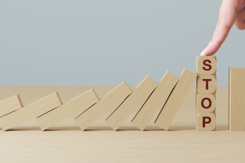 Hand stopping dominoes from falling