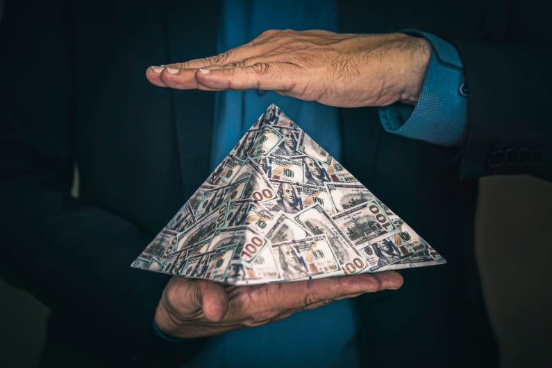 Man holding pyramid made of cash