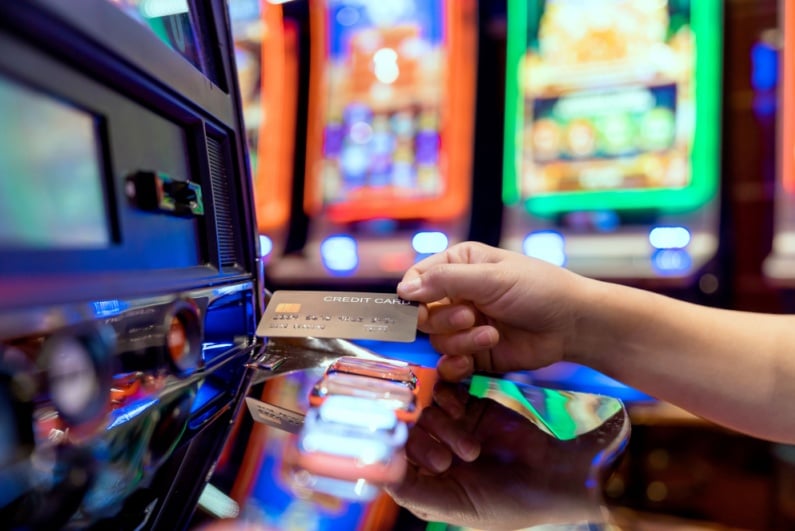 Person inserting credit card into gambling machine