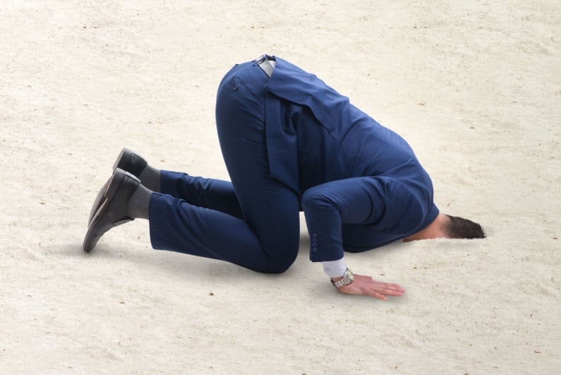 Businessman hiding head in sand