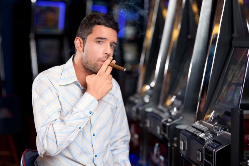 Man smoking cigar at slot machines