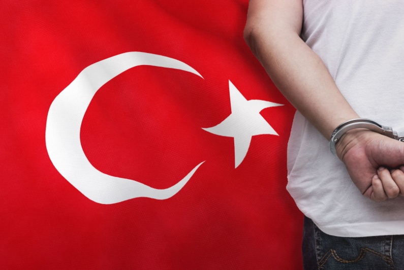 Man handcuffed with Turkish flag backdrop