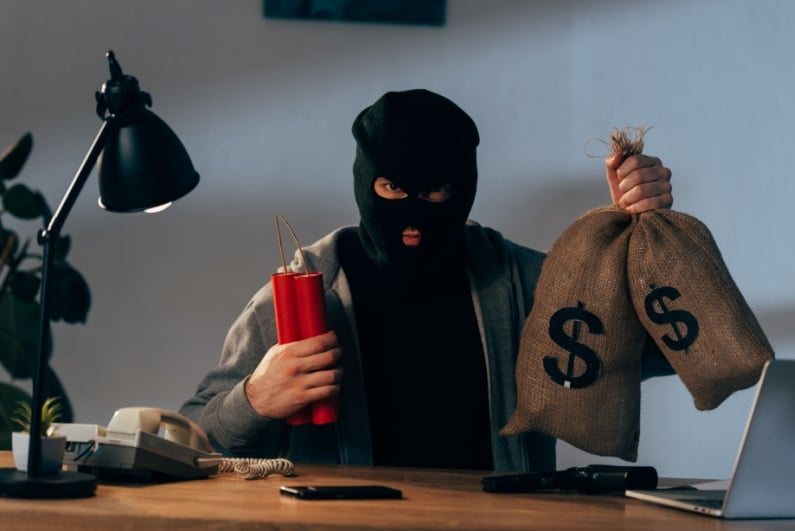 Masked man holding bags of money and dynamite