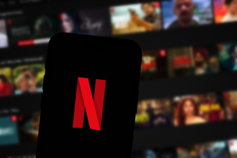 Netflix logo on phone with TV in background