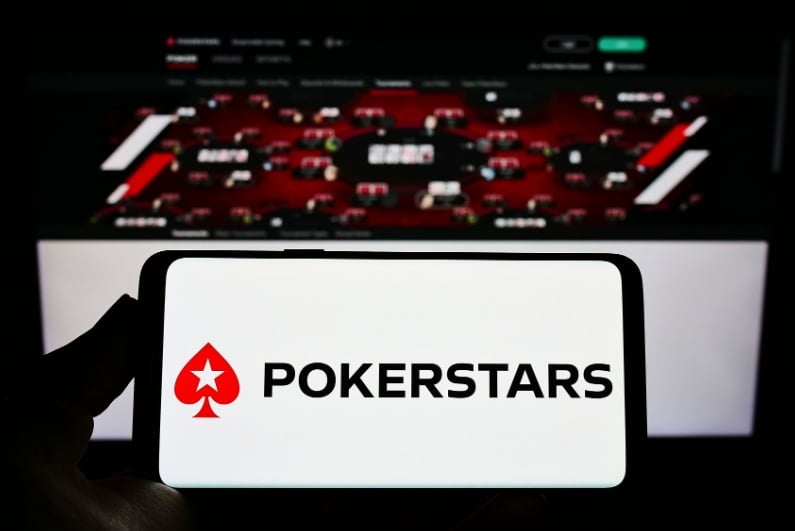 PokerStars logo on phone with poker tables on screen in background