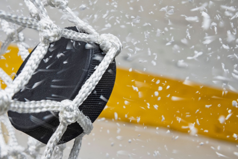 Closeup of hockey puck hitting back of net