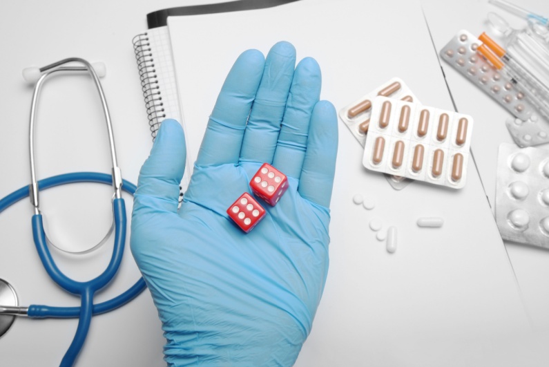 Pills next to a gloved hand holding dice