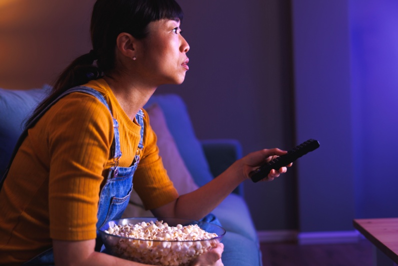 Woman watching television with bowl of popcorn