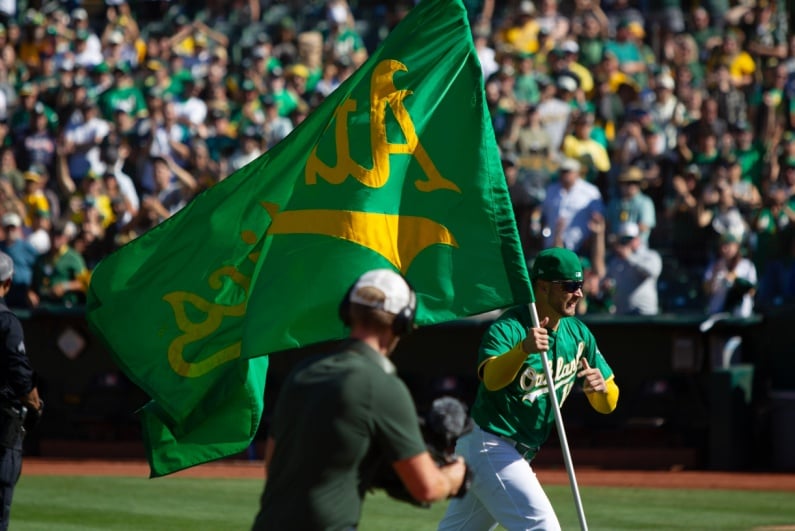 Athletics player running with team flag after last game in Oakland