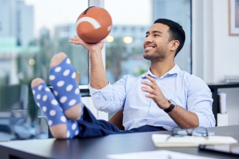 Happy businessman kicking back and twirling a football