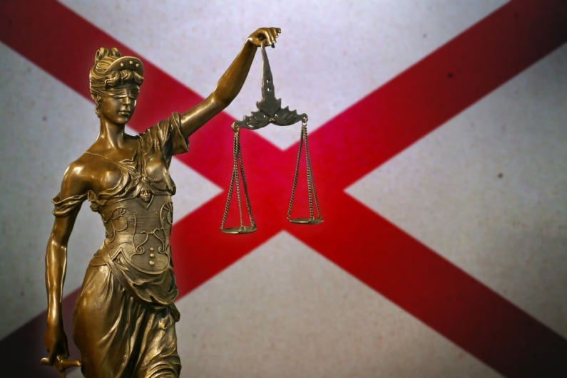 Lady Justice against an Alabama flag